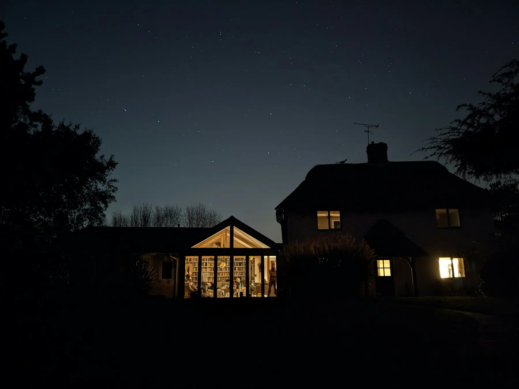 A house at night under the stars, windows lit